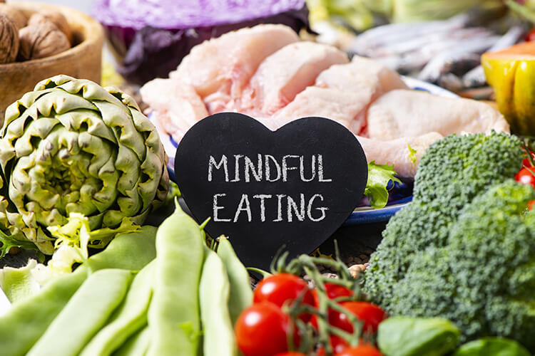 A heart with the words 'mindful eating' surrounded by an assortment of colorful vegetables.