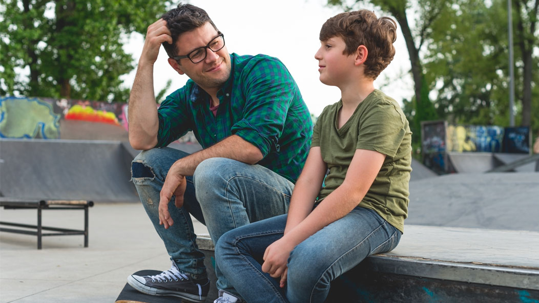 Parent talking to his son sitting at the skatepark