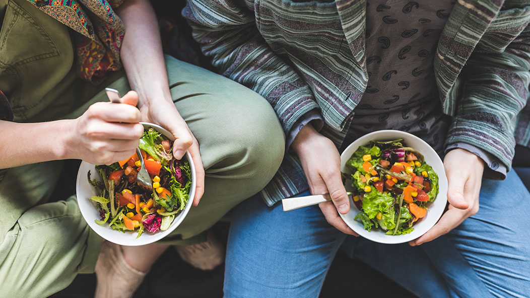 Couple eating healthy salad at home on the sofa
