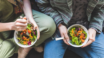 Couple eating healthy salad at home on the sofa