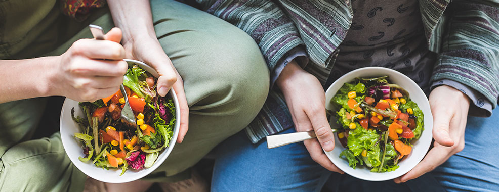 Couple eating healthy salad at home on the sofa