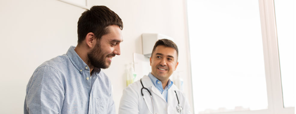 Men sitting at a doctor's office with a provider next to him