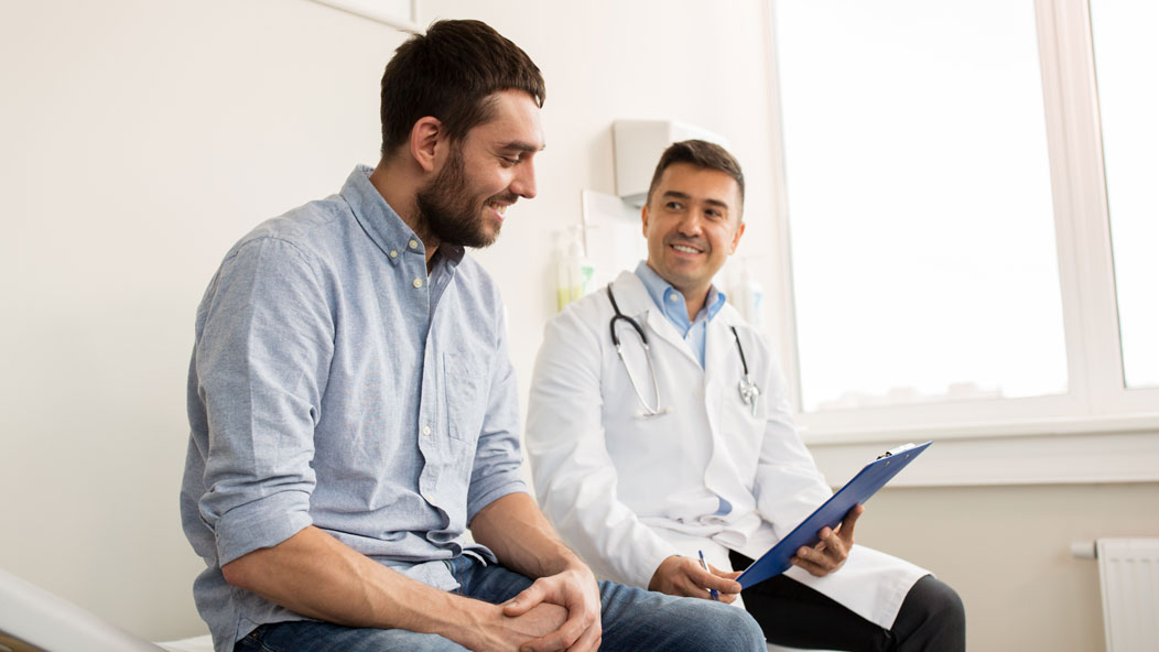 Man sitting at a doctor's office with a provider next to him