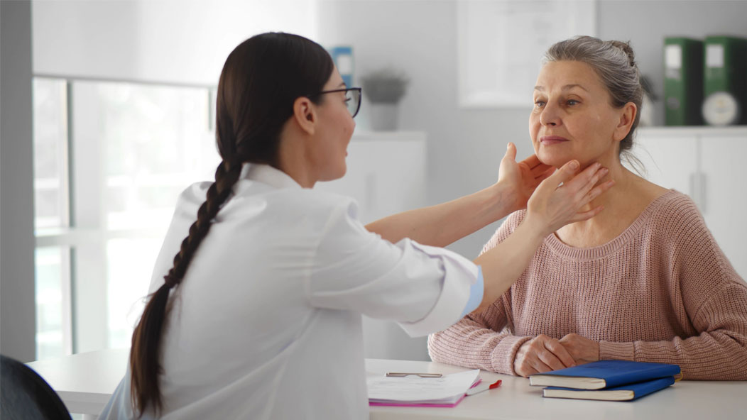 Professional physician checking neck lymph nodes of senior woman 