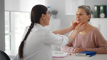 Professional physician checking neck lymph nodes of senior woman 