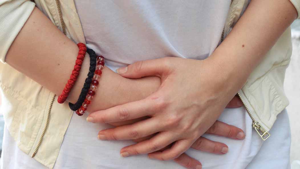 A close-up of a person with irritable bowel syndrome grasping their stomach with both hands.