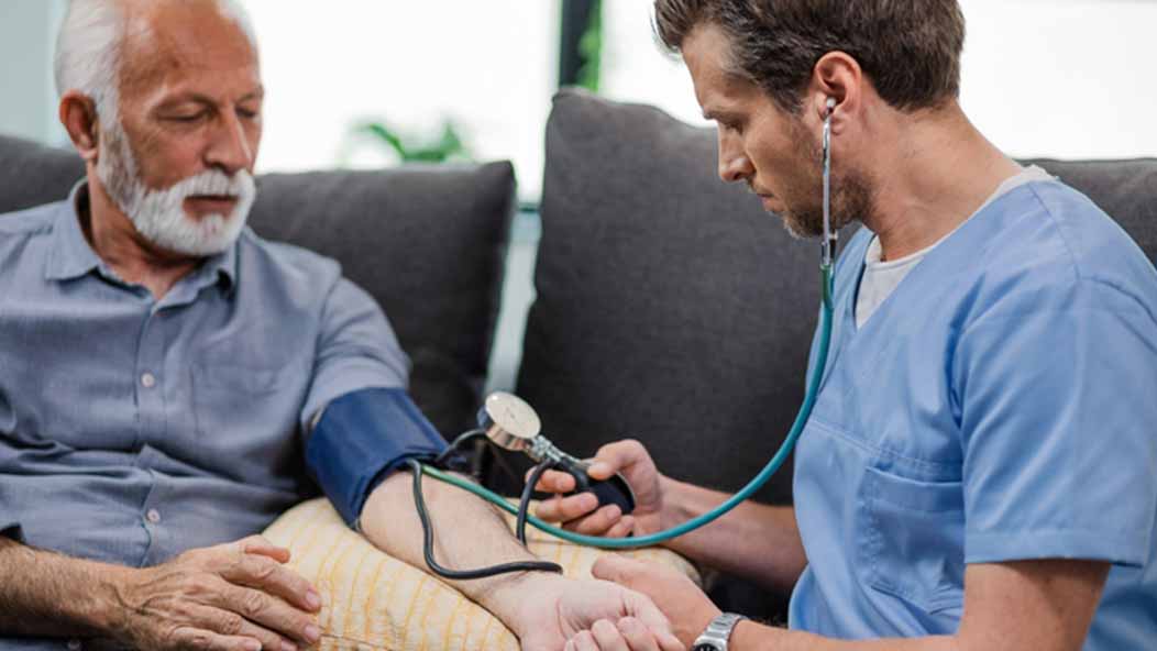 A senior man has his blood pressure taken by a nurse.