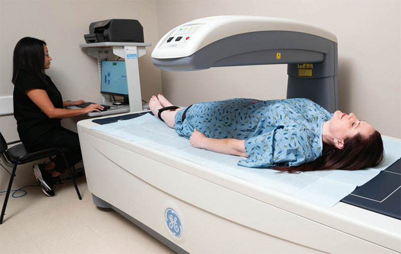 A medical professional runs a Dexa scan as a patient lies on a table.