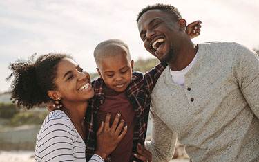 Mother, father, and son share a laugh on the beach on vacation.