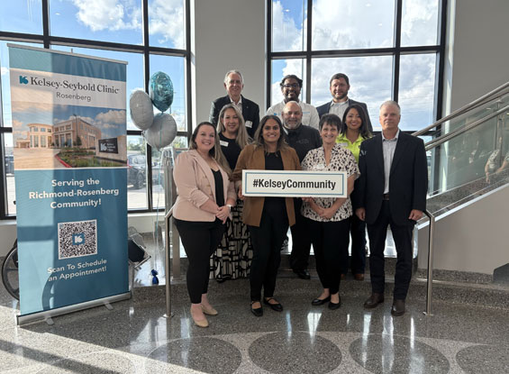 kelsey-Seybold team posing with a sign inside a clinic in Rosenberg